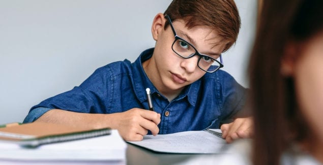 Teen writing in his notebook at school.