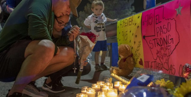 People praying at a memorial for victims of a mass shooting in El Paso, Texas