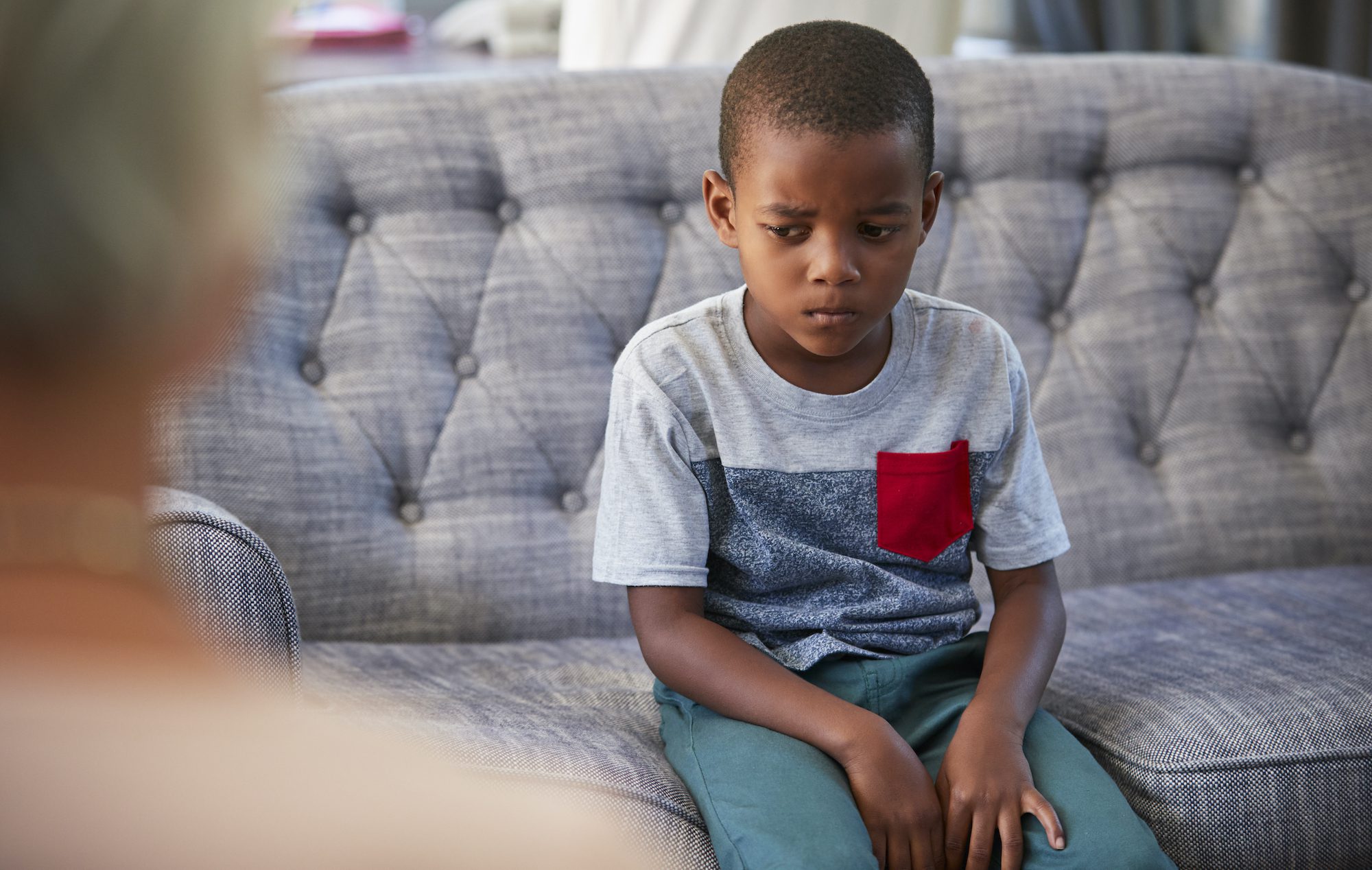 Sad boy sitting on a couch talking to a therapist