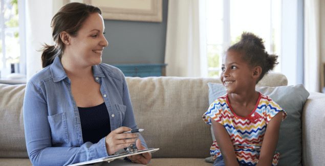 Child therapist talking to girl on a couch