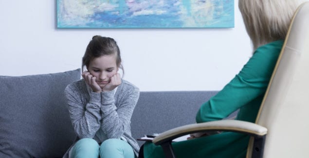 Teenage girl sitting on a couch talking to a therapist