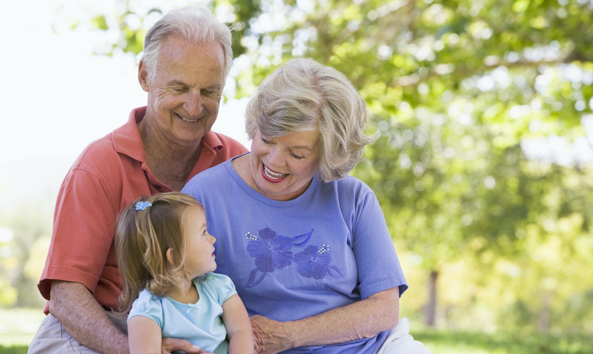 Grandparents sitting with their granddaughter outside