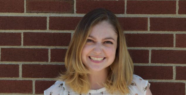 Headshot of Bianca Dempsey smiling in front of brick wall