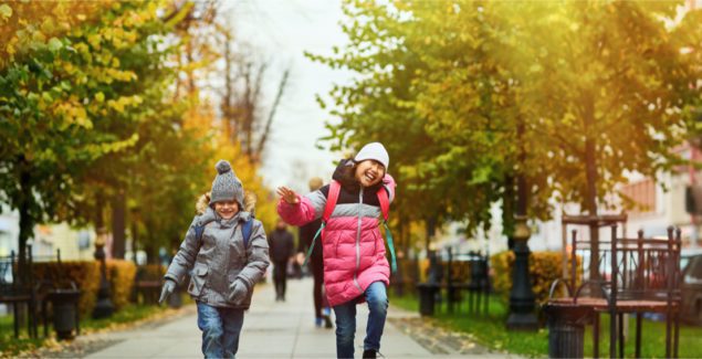 Nature and kids - Two happy kids in warm casualwear jumping over trottoire on their way to school on a fall morning