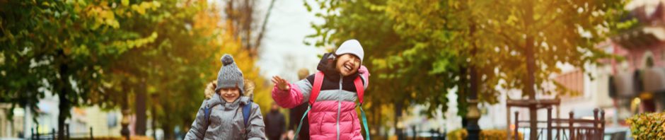 Nature and kids - Two happy kids in warm casualwear jumping over trottoire on their way to school on a fall morning