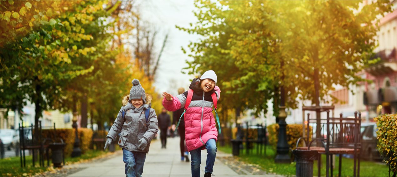 Nature and kids - Two happy kids in warm casualwear jumping over trottoire on their way to school on a fall morning