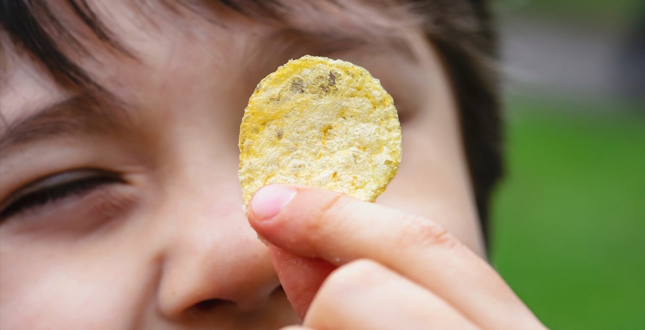 Relationship With Food - Cropped shot kid showing potato chips, Selective focus face of happy boy looking at fired potato, Close up Child eating potato crisp for his snack