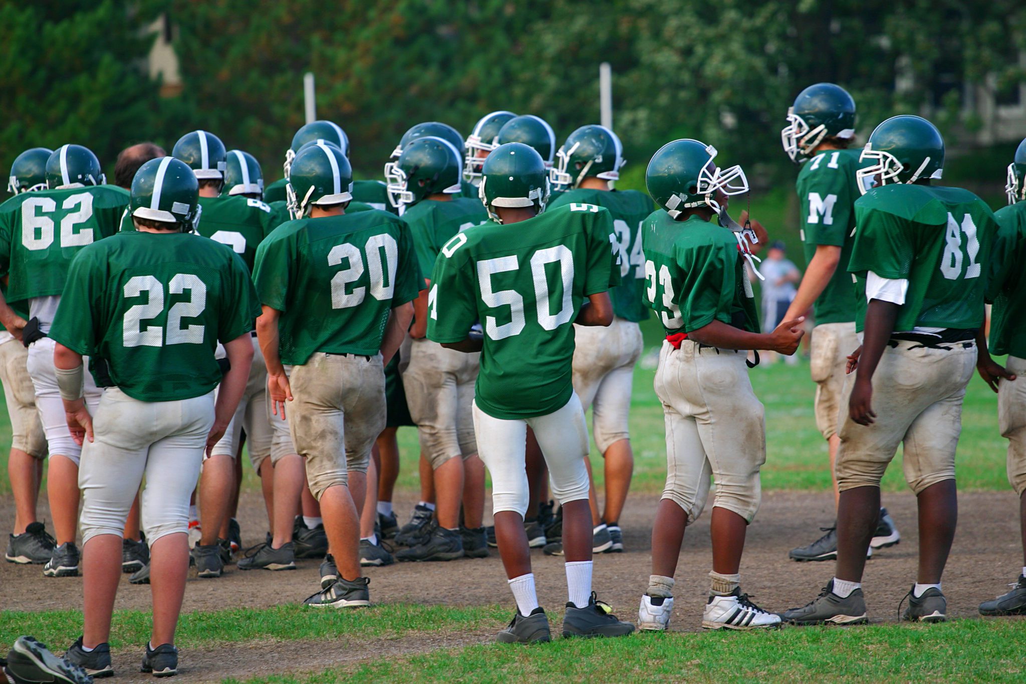 Teenagers on a football team wait for their turn on the field