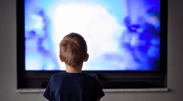 Behind shot of child watching blue tv screen