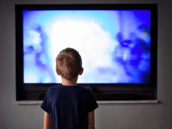 Behind shot of child watching blue tv screen