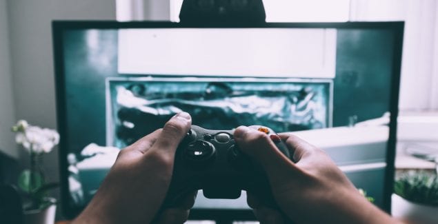 person holding game controller in-front of television