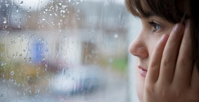 hurricanes storms - young child looking out of window on rainy day