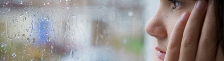 hurricanes storms - young child looking out of window on rainy day