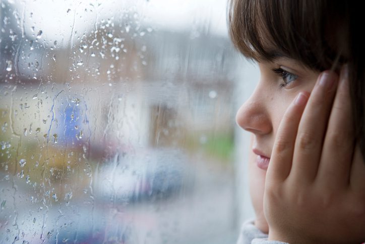 hurricanes storms - young child looking out of window on rainy day