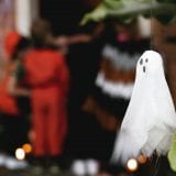 Ghost decoration in foreground of kids trick-or-treating