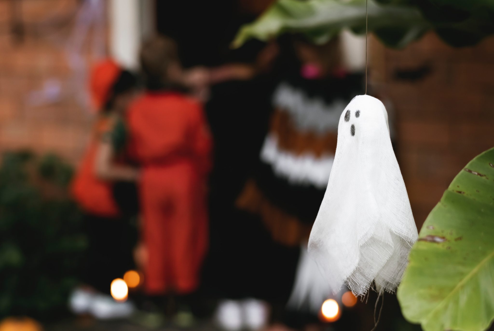 Ghost decoration in foreground of kids trick-or-treating