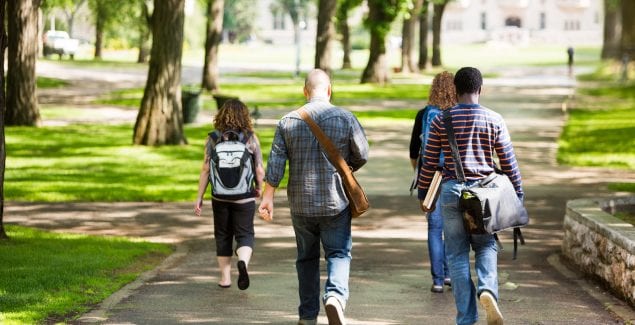 University students with backpacks walking on campus road