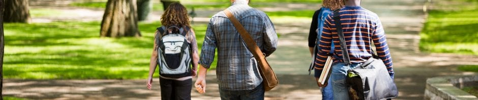 University students with backpacks walking on campus road