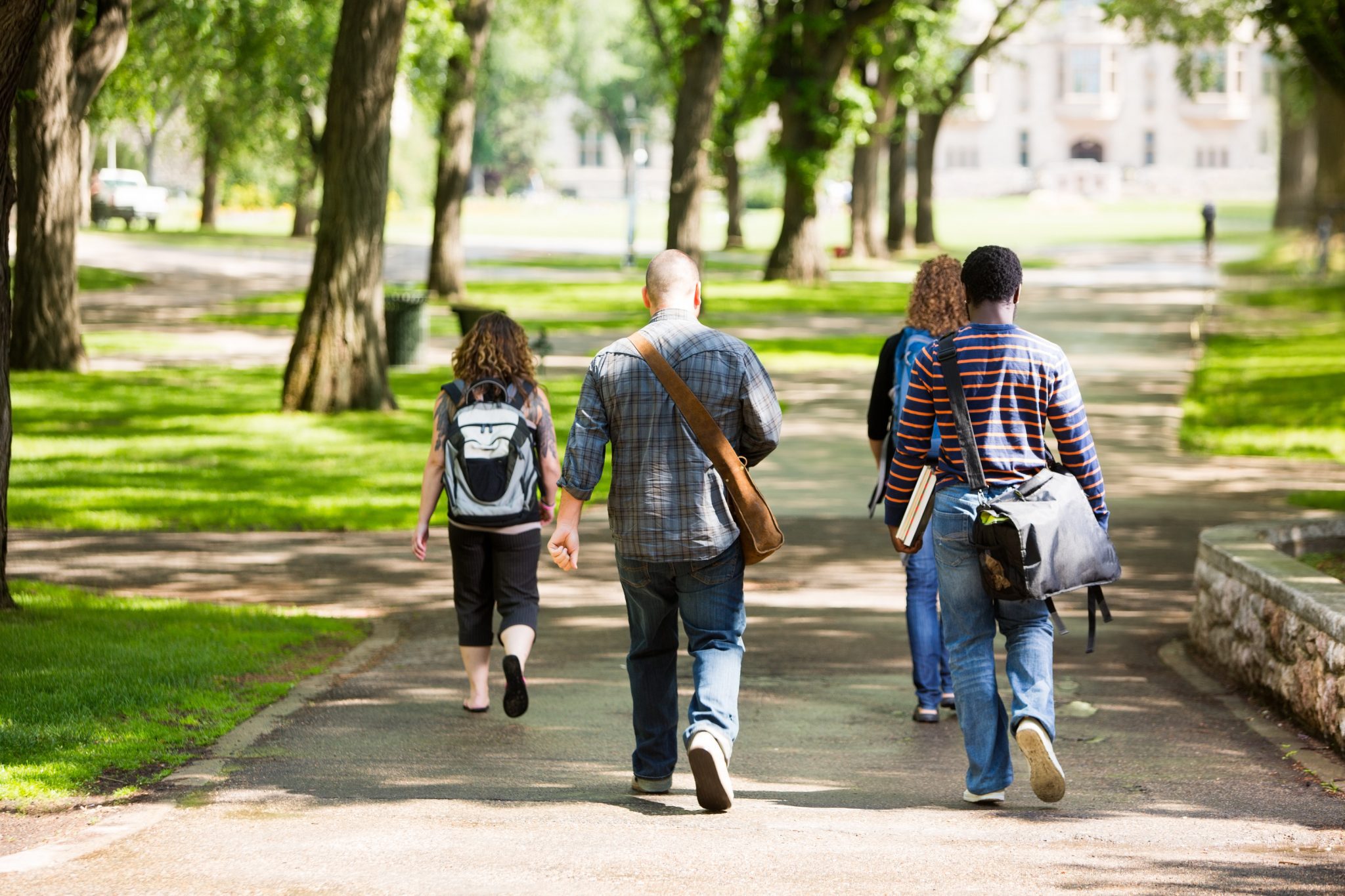 University students with backpacks walking on campus road