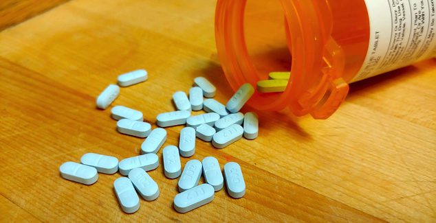 Prescription pill bottle sideways on counter with sertraline pills spilling out