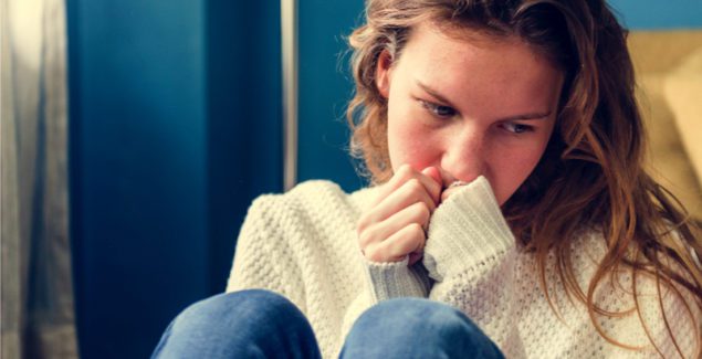 Self-cutting Young girl sitting with long sleeves looking sad