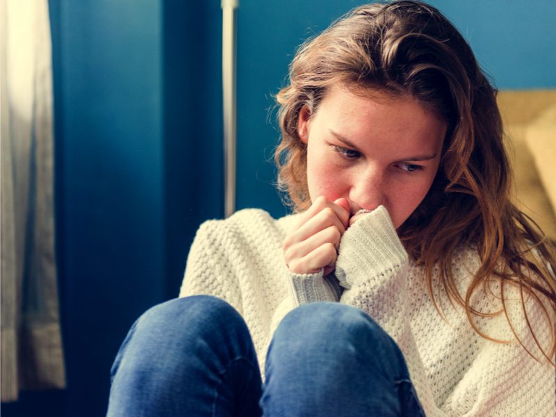Self-cutting Young girl sitting with long sleeves looking sad