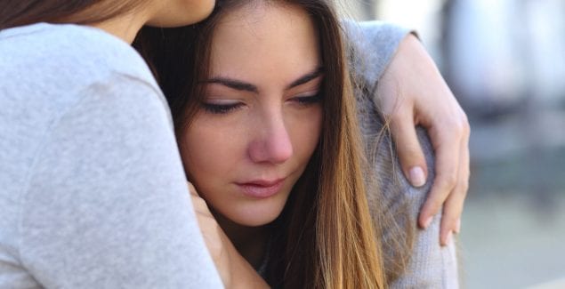 crying teen being held by friend after disclosing sexual assault