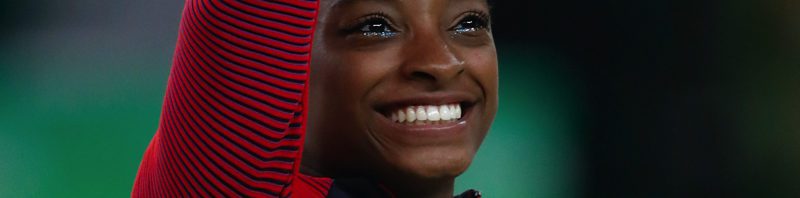 Simone Biles waving and smiling at the 2016 Rio Olympics