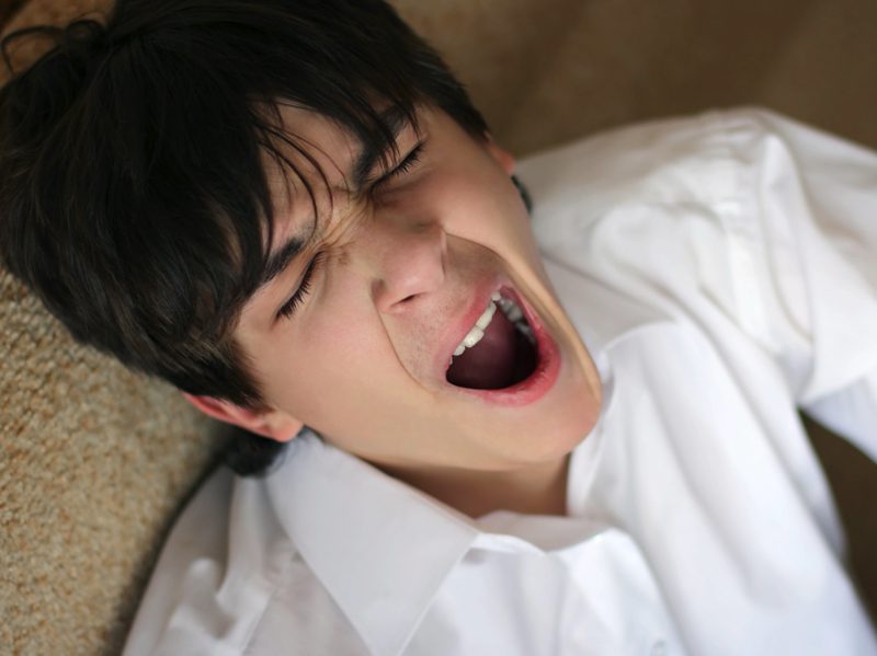 About Sleep - Teen yawning while leaning back on sofa