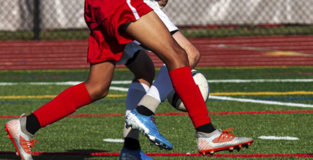 Sports Injury - Close up foot movement on soccer field, two players legs intertwined