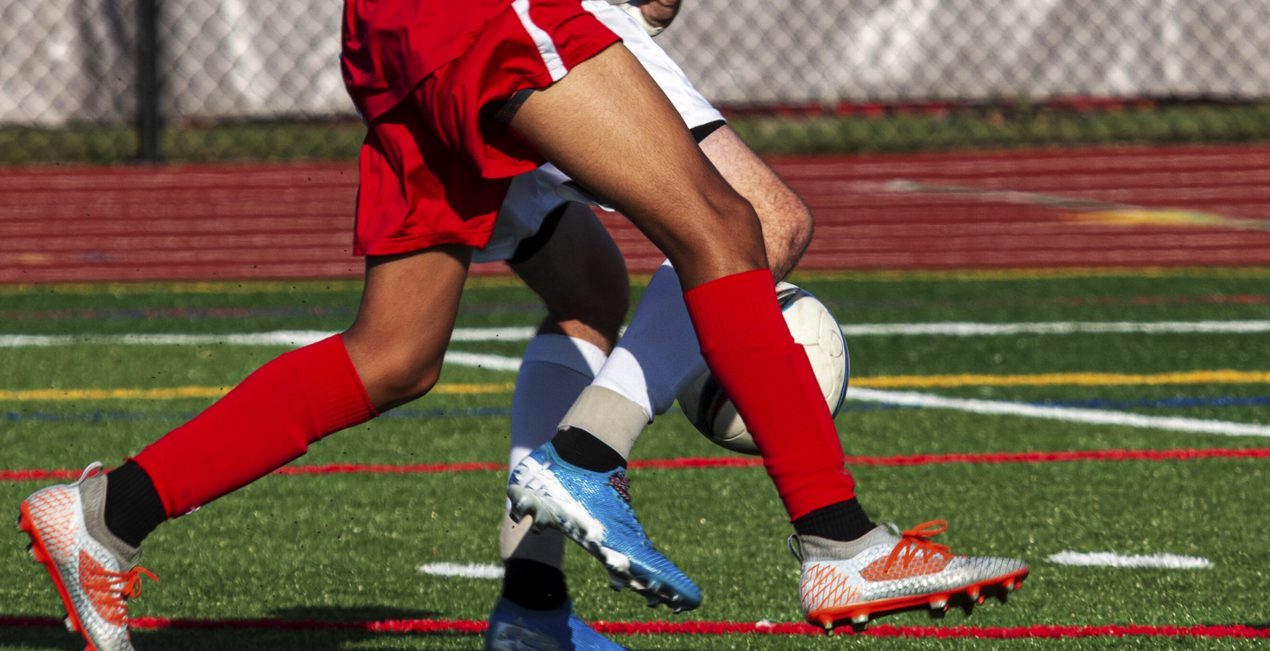 Sports Injury - Close up foot movement on soccer field, two players legs intertwined