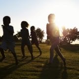 Silhouetted elementary school kids running in a field