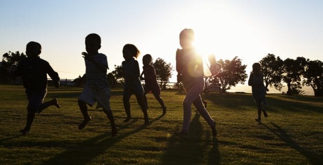 Silhouetted elementary school kids running in a field