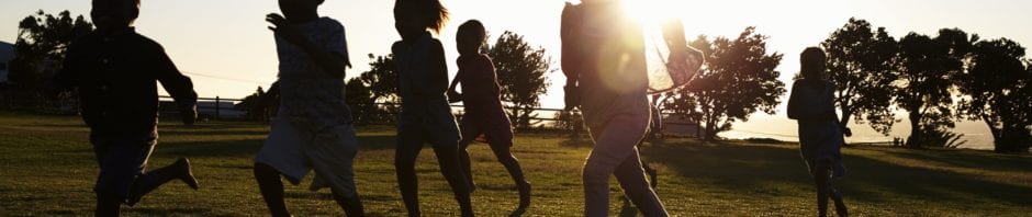 Silhouetted elementary school kids running in a field