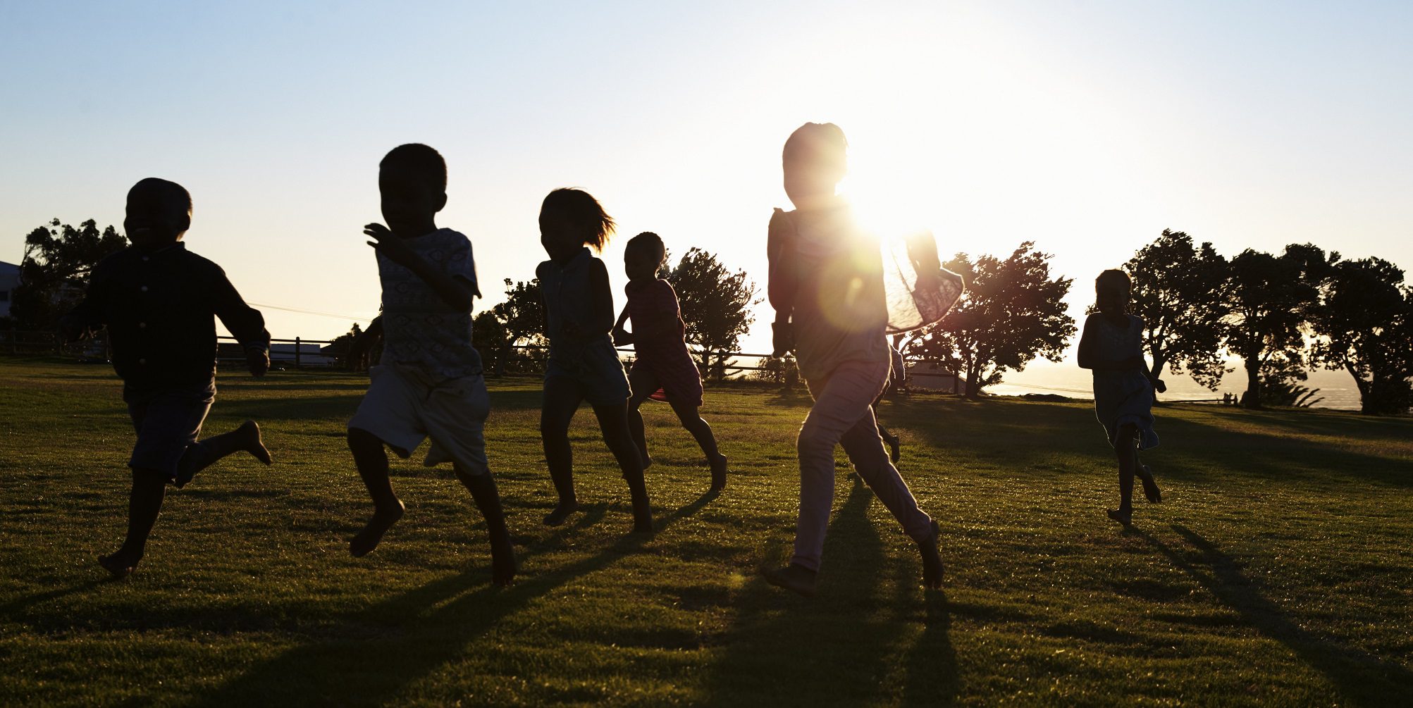 Silhouetted elementary school kids running in a field