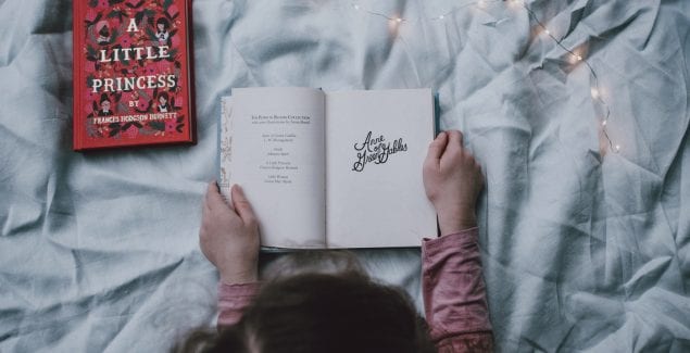 Child holding open a story book, surrounded by magical lighting
