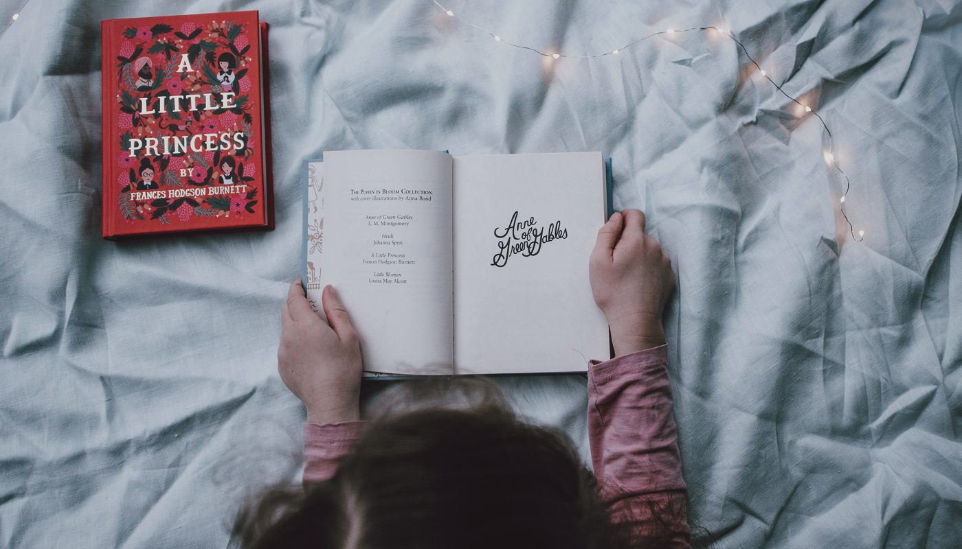 Child holding open a story book, surrounded by magical lighting