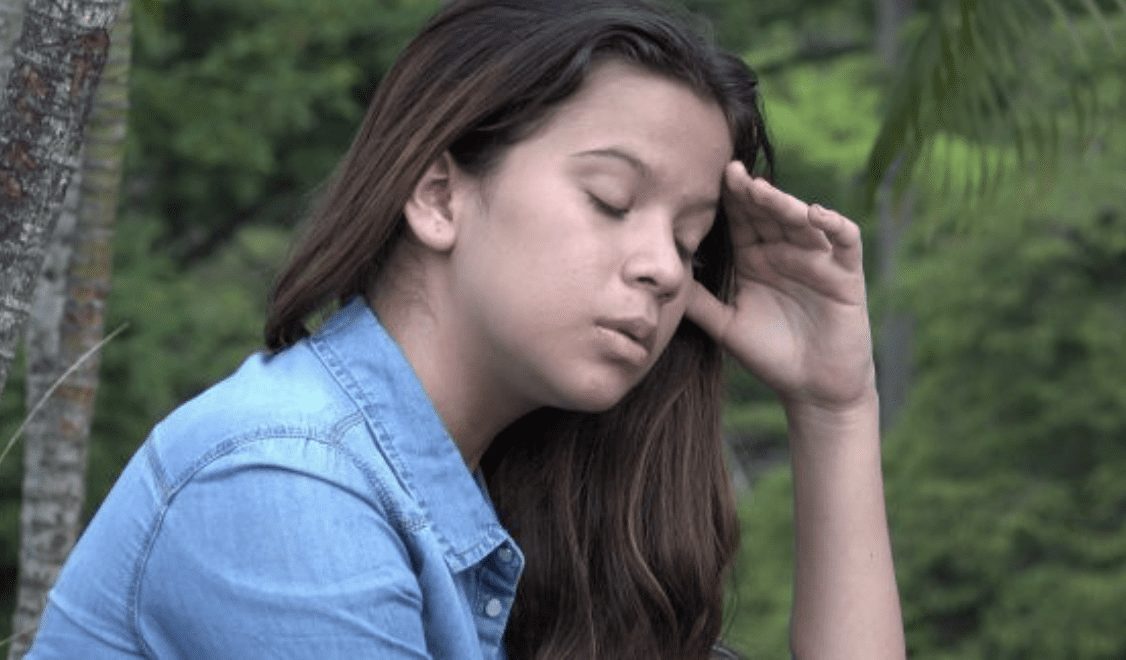 Teen girl leaning head on hand looking stressed