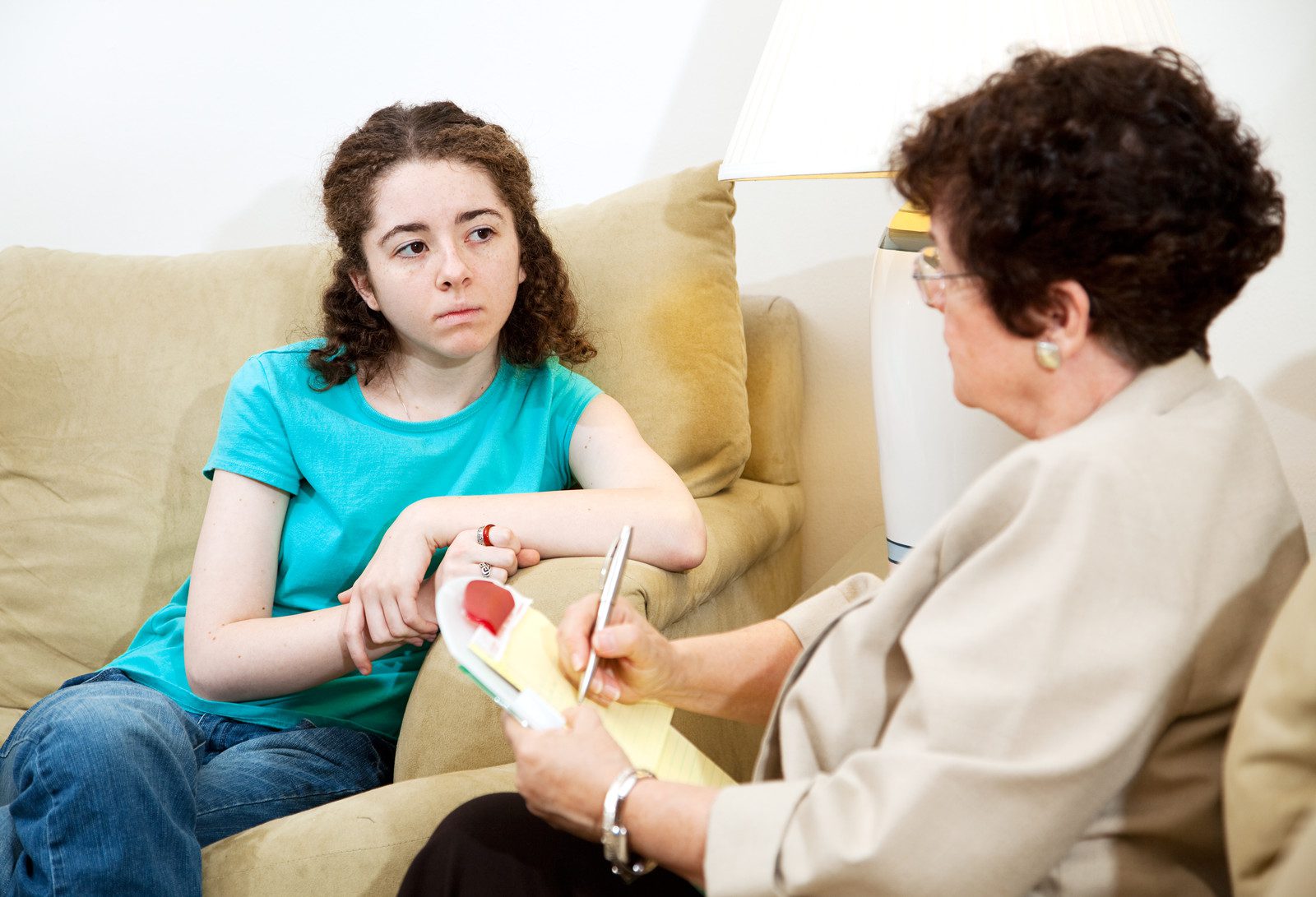 Seemingly depressed teen girl in therapy with a psychologist.