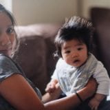 Mom holding baby while sitting on a couch
