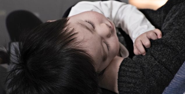 Young toddler asleep on parent's lap