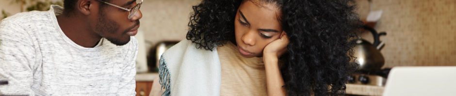 Trauma - Young african american couple sitting at table having serious conversation