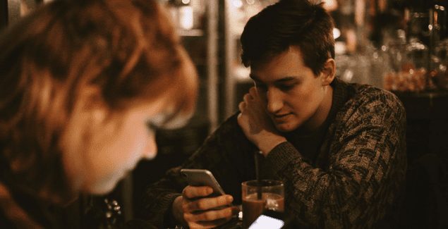 Two teens checking their phones