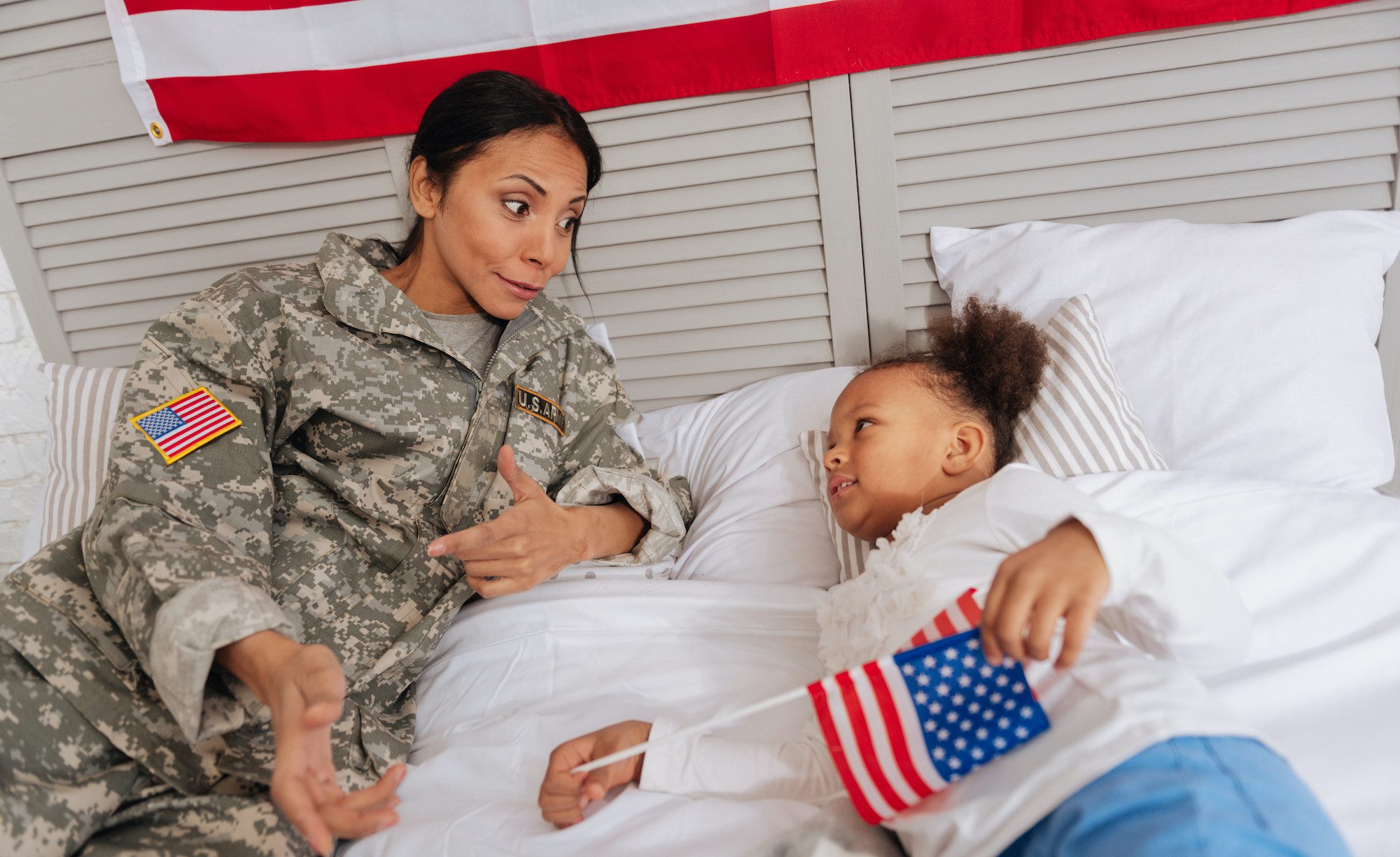 Veterano mãe a ter uma conversa com sua filha em uma cama