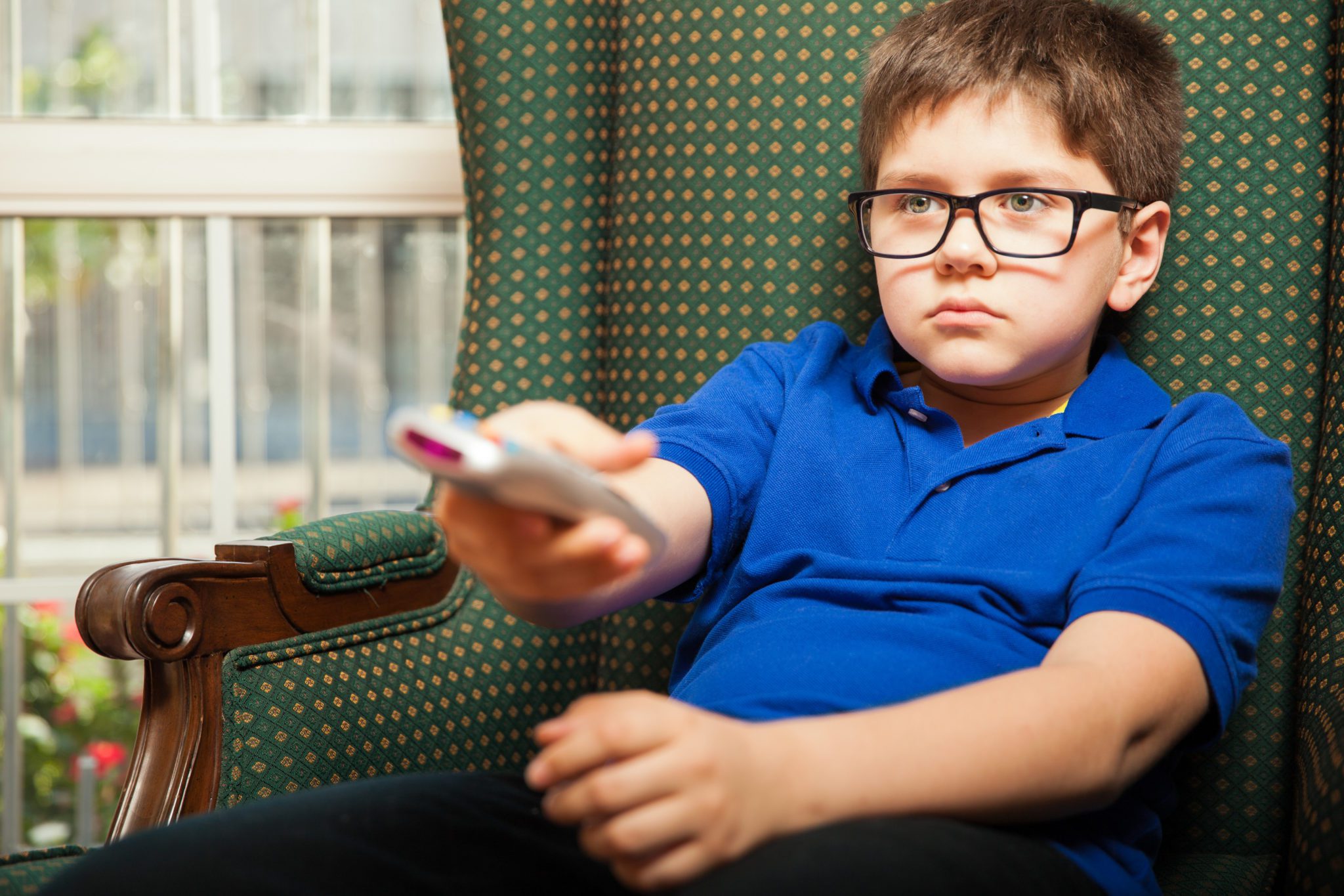 Young male child sitting leaning back on sofa flipping through channels