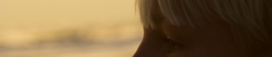 Child Stress - Profile of caucasian pre-teen boy on beach at sunset.