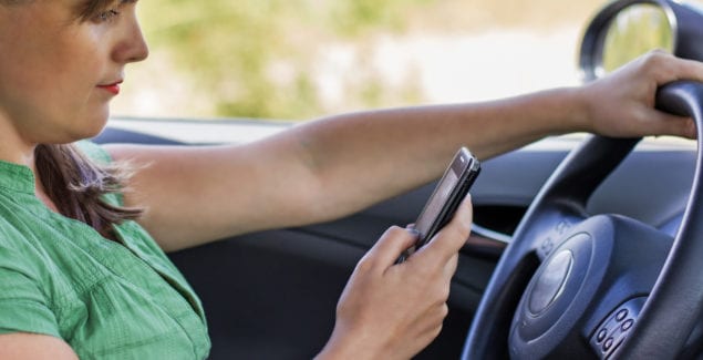 Woman driver reading a text message on a mobile