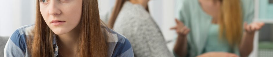 Image of a girl on her own while two others chat happily