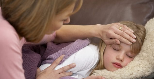 The Flu - young girl lying on couch looking ill and parent holding hand over her head