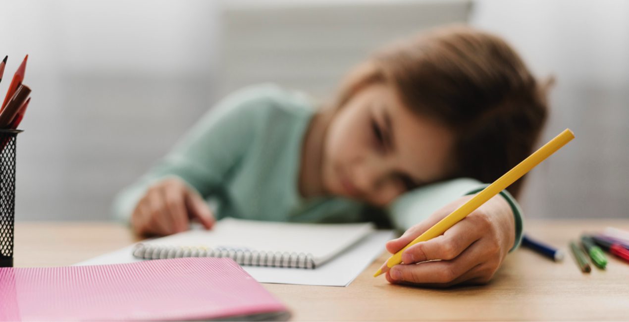Trauma - Sad girl resting head on desk with pencil in hand